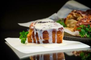 cooked baked sweet Cinnabon with cream in baking paper . photo