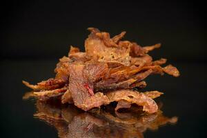 handful of dried meat marinated with spices, isolated on a black background. photo