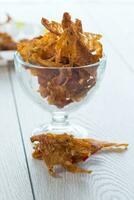 dried meat with spices in a glass bowl, light wooden background. photo