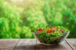 AI generated Full bowl of fresh salad on a wooden table against the background blur green leaves bokeh. generative ai. photo