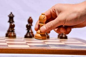 a person is holding a wooden chess piece photo