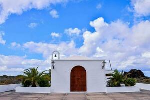 a white church with palm trees and clouds in the background photo