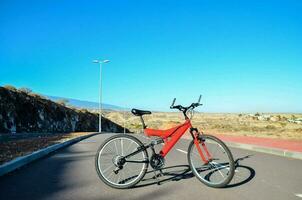 un rojo bicicleta estacionado en el lado de el la carretera foto