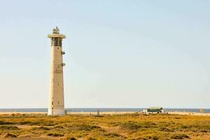 a lighthouse on the beach with a blue sky photo