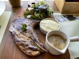 Grilled or fried pork chops on the bone with salad and mashed potatoes served on wooden board photo