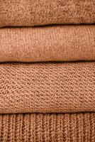 stack of knit sweaters peach color of the year 2024 photo