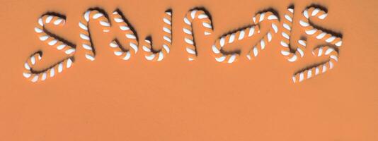 Flat lay Christmas composition with frame of candy canes on a Peach Fuzz background. photo