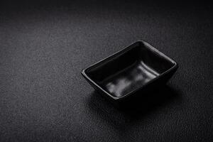 Beautiful empty black ceramic gravy boat on a textured concrete background photo