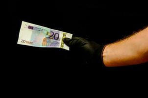 a person in black gloves holding a twenty euro bank note photo