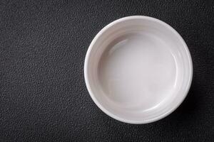 Beautiful empty white ceramic gravy boat on a textured concrete background photo