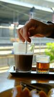 A woman's hand is using a spoon to stir things into a drink glass. video