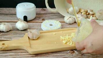 A man's hand is pouring the crushed garlic into a wooden plate. video