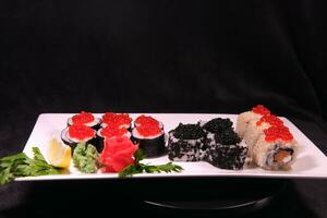 Three types of sushi rolls with white and black sesame seeds with black paddlefish caviar, red chum salmon caviar and pink salmon on one plate. Delicious food, beautiful presentation. photo