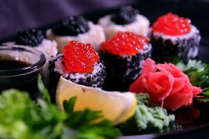 Three types of sushi rolls with white and black sesame seeds with black paddlefish caviar, red chum salmon caviar and pink salmon on one plate. Delicious food, beautiful presentation. photo