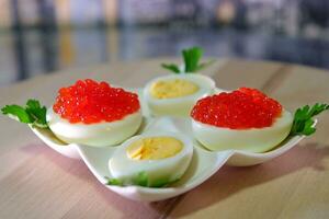 Put black caviar on an egg to serve delicious healthy food Halves of a hardboiled chicken egg with red caviar on a wooden background. photo