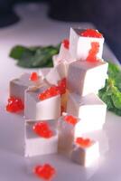 Feta cheese with red caviar decorated with herbs on a white plate. High quality photo