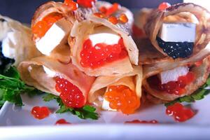 Pancakes with red caviar , black caviar with Feta cheese decorated with herbs. Delicious Healthy Food photo