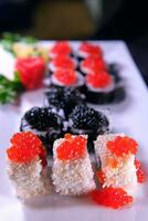 Three types of sushi rolls with white and black sesame seeds with black paddlefish caviar, red chum salmon caviar and pink salmon on one plate. Delicious food, beautiful presentation. photo