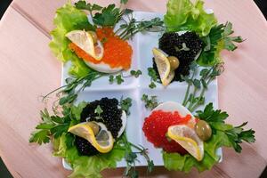 lujoso aperitivo de codorniz huevos con un pegar de calamar, camarón y negro caviar en patata y queso papas fritas foto