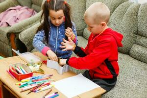primary school children boy and girl are engaged in creative hand-made art at the table at home photo