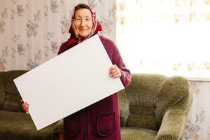 elderly woman holding a blank vertical canvas in her hands. Empty frame for text or photo. woman with mockup poster photo