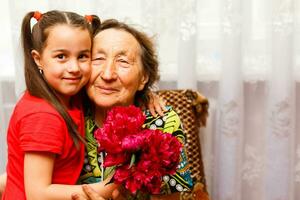 little girl giving her great grandmother a pink flower photo