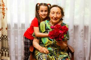 Little girl visiting her ill grandmother giving flowers photo