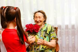 Little girl visiting her ill grandmother giving flowers photo