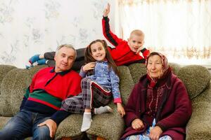 nietos saltando en sofá con su abuelos en el vivo habitación foto