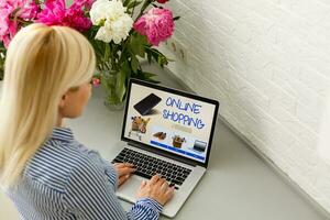 Online shopping website on laptop screen with female hands typing photo