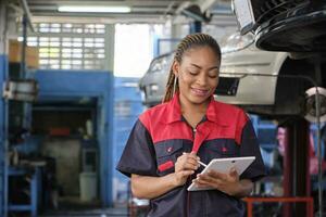 Black female professional mechanic, supervisor engineer, inspects repair work checklists with tablet at garage, service car maintenance, and fixing specialist occupations in auto transport industry. photo