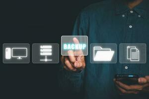 Backup storage data internet technology business concept, Young man using smartphone with VR screen backup icon on desk. photo