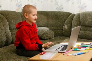 Happy boy sitting at his desk With laptop computer photo