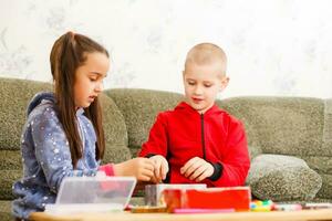 pequeño niñito niña y chico concentrado trabajo juntos. chico y niña aprender y jugar juntos a el mesa. niños disfrutar mano escribiendo. amistad foto