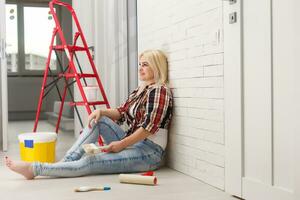 Beautiful young woman painting wall in room photo