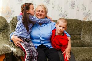 Grandmother and grandchildren sitting together on sofa in living room photo