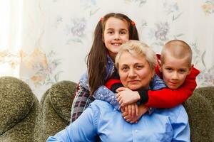 Grandmother and grandchildren sitting together on sofa in living room photo