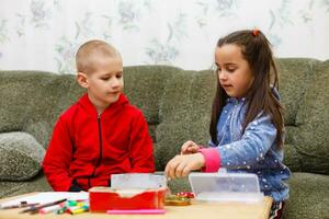 pequeño niñito niña y chico concentrado trabajo juntos. chico y niña aprender y jugar juntos a el mesa. niños disfrutar mano escribiendo. amistad foto