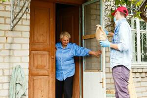 An elderly woman stays at home. Food delivery in a medical mask. photo