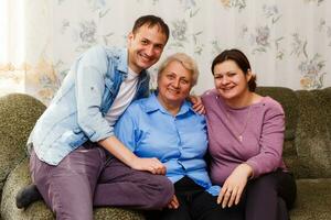 Grown up adult smiling grandchildren embraces elderly grandmother glad to see missing her, visit of loving relatives enjoy communication, cuddle as symbol of connection, love and support concept photo