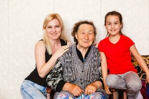 mayor mujer abrazando nieta mientras sentado en sofá a hogar foto