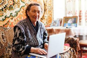 Elder woman using a laptop computer at home photo