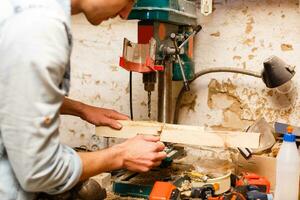 Satisfied cheerful joyful smiling woodmaster is standing near desktop in his workshop, workstation photo