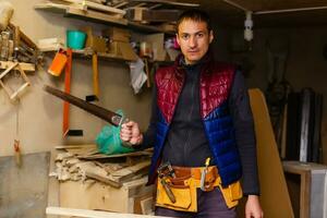 Satisfied cheerful joyful smiling woodmaster is standing near desktop in his workshop, workstation photo