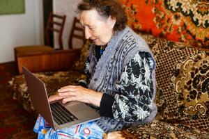 mayor mujer utilizando un ordenador portátil computadora a hogar foto
