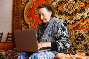technology, old age and people concept - happy senior woman having video call at home in evening photo