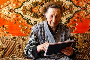 technology, old age and people concept - happy senior woman having video call at home in evening photo