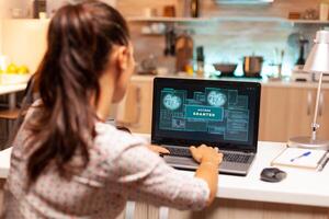 Hacker woman launching a cyberattack on bank firewall from home during night time. Programmer writing a dangerous malware for cyber attacks using performance laptop during midnight. photo