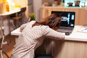 Sad woman because she lost on computer games during night time in home kitchen. Professional gamer playing online videop games on her personal computer. Geek cyber esport. photo