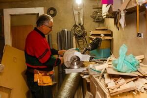 Satisfied cheerful joyful smiling woodmaster is standing near desktop in his workshop, workstation photo